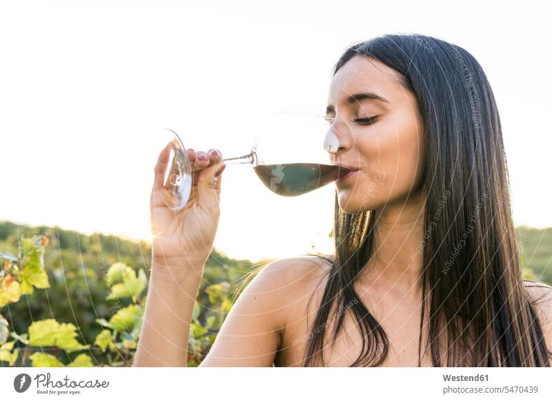 Italy, Tuscany, Siena, young woman drinking red wine in a vineyard at sunset Red Wine Red Wines females women sunsets sundown Alcohol alcoholic beverage