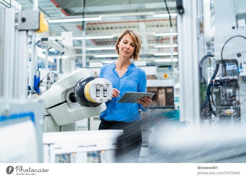 Businesswoman with tablet at assembly robot in a factory human human being human beings humans person persons caucasian appearance caucasian ethnicity european