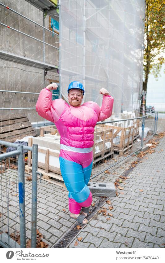 Portrait of a proud man wearing pink bodybuilder costume and hard hat at construction site human human being human beings humans person persons