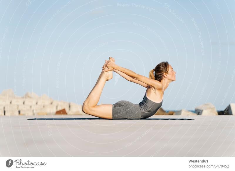 Sportswoman doing bow pose on sunny day color image colour image outdoors location shots outdoor shot outdoor shots daylight shot daylight shots day shots