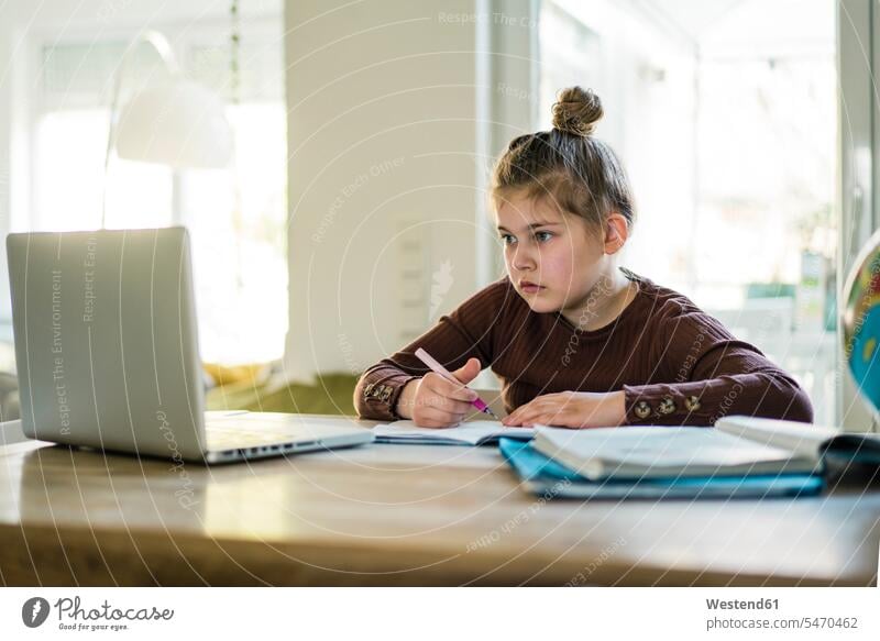 Girl writing in book while studying through laptop at home color image colour image indoors indoor shot indoor shots interior interior view Interiors day
