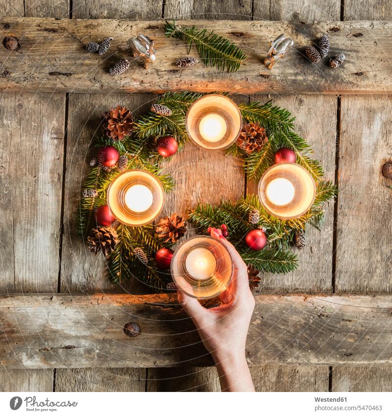 Hand of woman touching glass cover of candle burning on Advent wreath indoors indoor shot indoor shots interior interior view Interiors overhead view