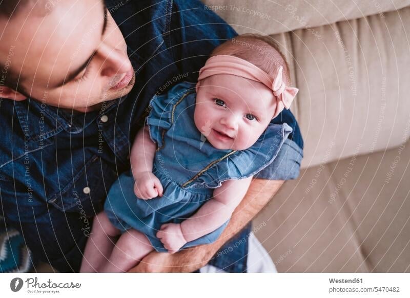 Cute baby girl being carried by father on sofa at home color image colour image indoors indoor shot indoor shots interior interior view Interiors day
