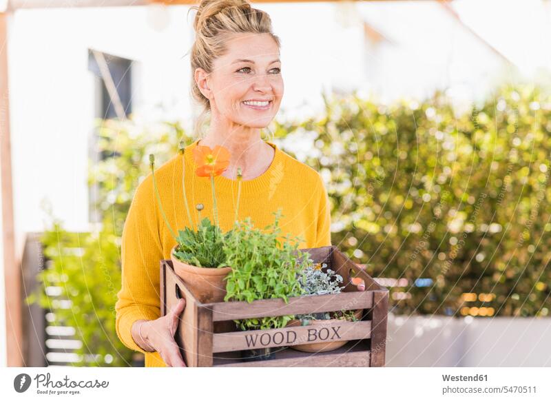 Portrait of happy mature woman with wooden box of plants on terrace jumper sweater Sweaters relax relaxing smile delight enjoyment Pleasant pleasure indulgence