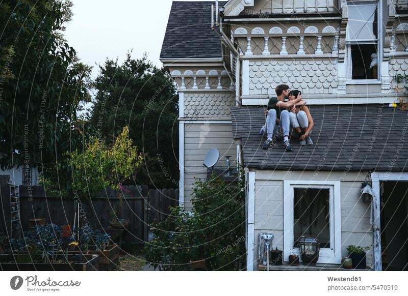 Couple sitting on roof kissing Seated Roof kisses couple twosomes partnership couples people persons human being humans human beings relaxation relaxing bonding
