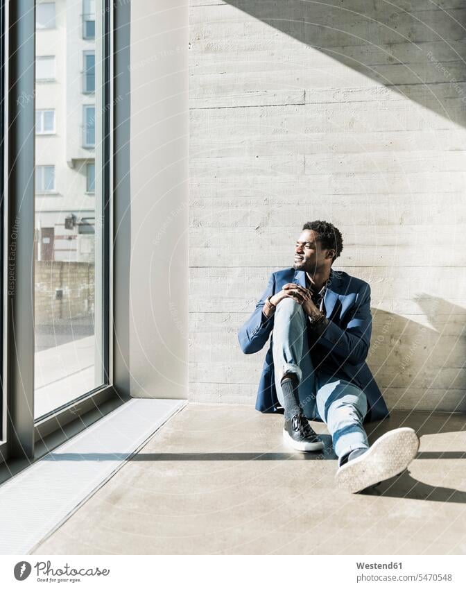 Businessman sitting on the floor in sunshine looking out of window windows Business man Businessmen Business men floors sunlight Sunlit Seated view seeing