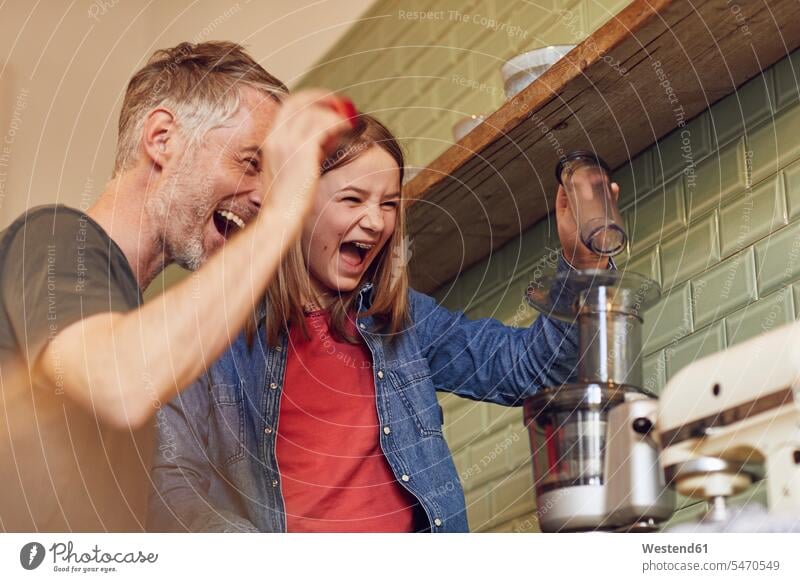 Playful father and daughter in kitchen preparing a smoothie devices blender Electric Mixer food mixer mixers delight enjoyment Pleasant pleasure Cheerfulness