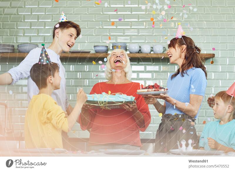 Mother and sons celebrating grandmother's bithday in their kitchen generation celebrate partying delight enjoyment Pleasant pleasure Cheerfulness exhilaration