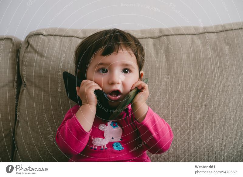 Baby girl playing with two mobilephones at home on the phone call telephoning On The Telephone calling portrait portraits playful Smartphone iPhone Smartphones