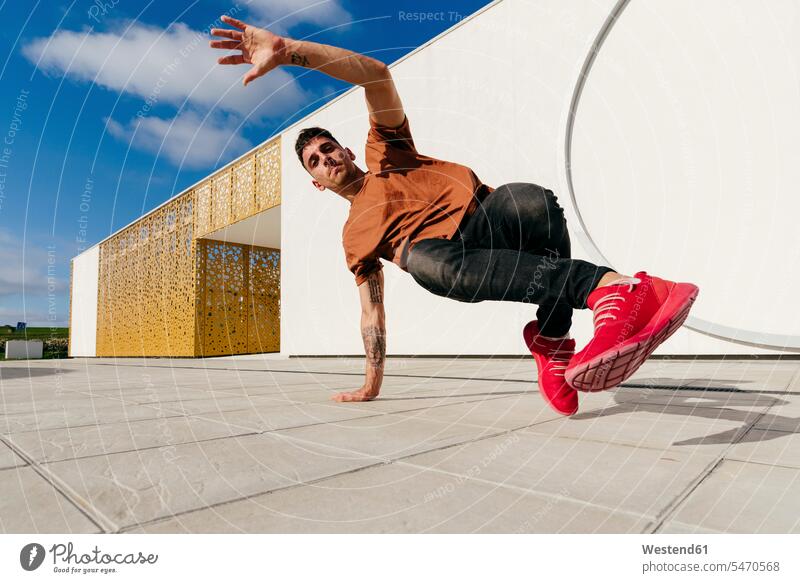 Young man dancing on footpath during sunny day color image colour image outdoors location shots outdoor shot outdoor shots daylight shot daylight shots
