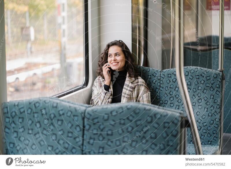 Smiling young woman on the phone on a subway windows pane panes window glass window glasses Window Pane windowpanes transport railroad railroads Railways