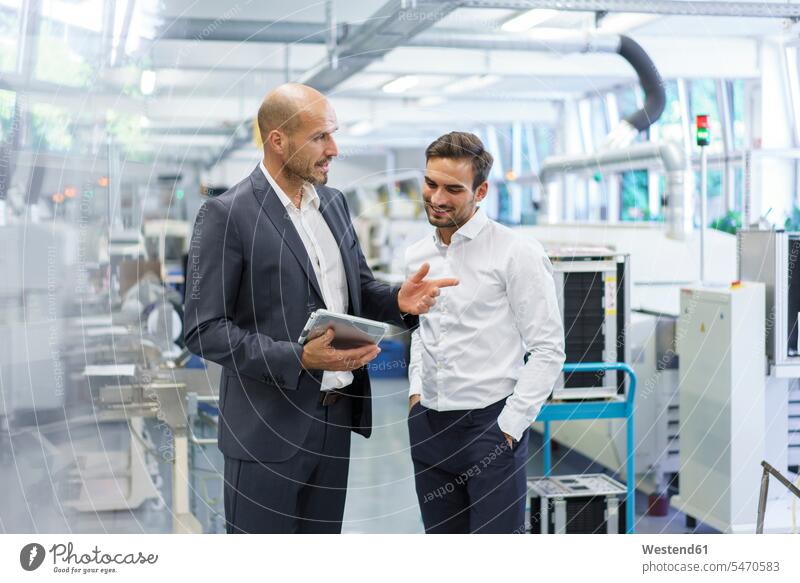 Confident businessman discussing with engineer over digital tablet at factory color image colour image indoors indoor shot indoor shots interior interior view