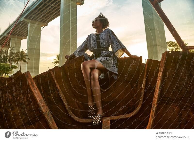 Woman wearing dress and sitting on rusty ship wreck human human being human beings humans person persons African black black ethnicity coloured 1
