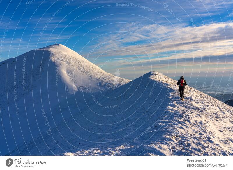 Italy, Province of Pesaro and Urbino, Male hiker ascending snowcapped peak of Monte Acuto outdoors location shots outdoor shot outdoor shots day daylight shot