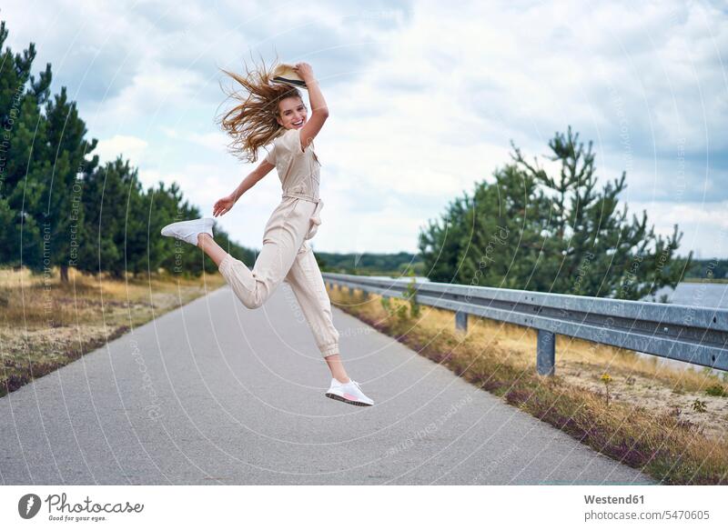 Cheerful woman jumping on rural road human human being human beings humans person persons caucasian appearance caucasian ethnicity european 1 one person only