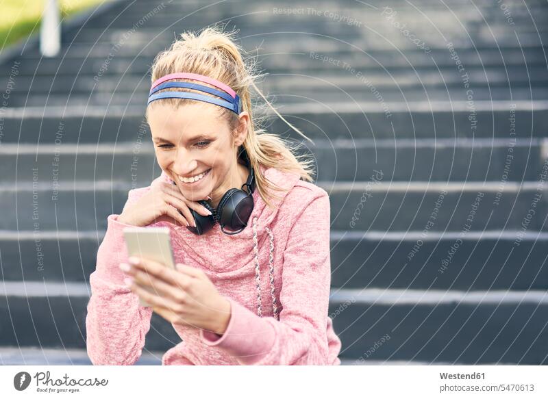 Sporty woman sitting on stairs, using smartphone human human being human beings humans person persons caucasian appearance caucasian ethnicity european 1