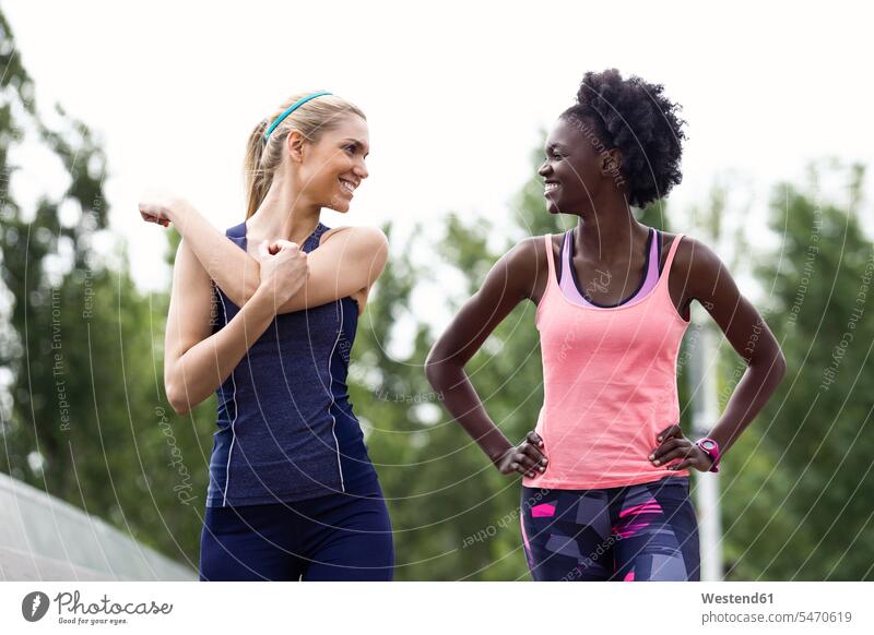 Two sporty young women talking and relaxing after running in the city relaxed relaxation sportive sporting athletic woman females town cities towns speaking