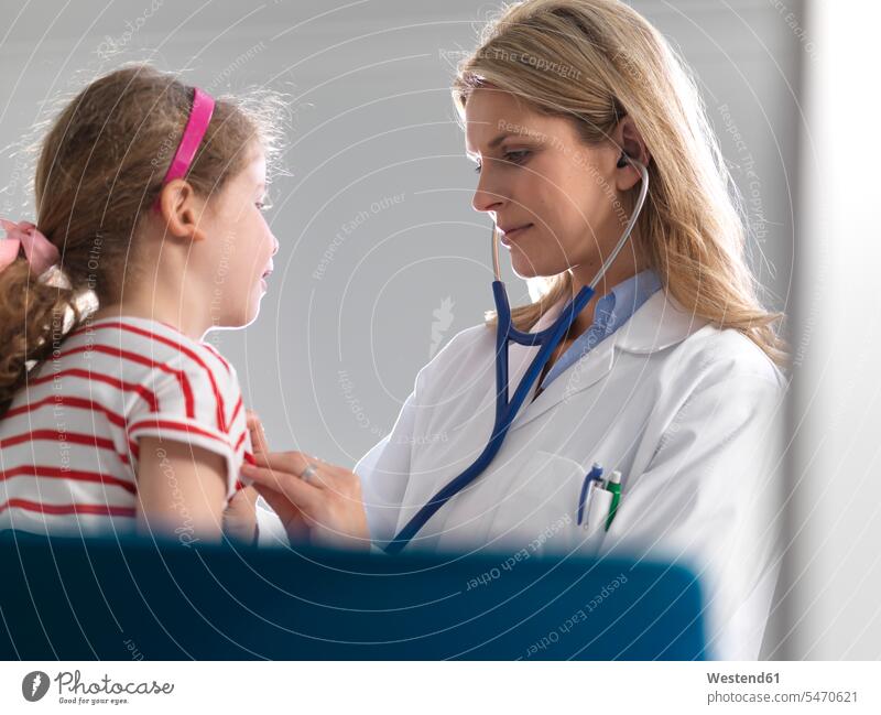 Female doctor listening to a young girl heart using a stethoscope in a clinic human human being human beings humans person persons caucasian appearance
