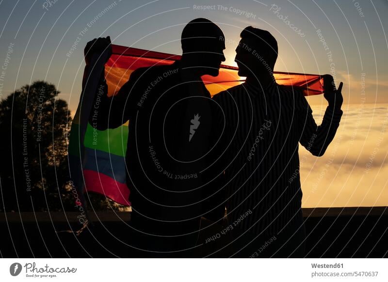 Silhouette of gay couple with gay pride flag in backlight human human being human beings humans person persons caucasian appearance caucasian ethnicity european