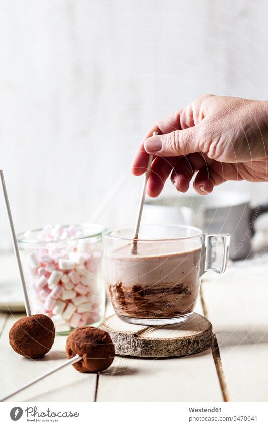 Hand of woman mixing hot chocolate by truffle lollipops and marshmallows on table at home color image colour image indoors indoor shot indoor shots interior