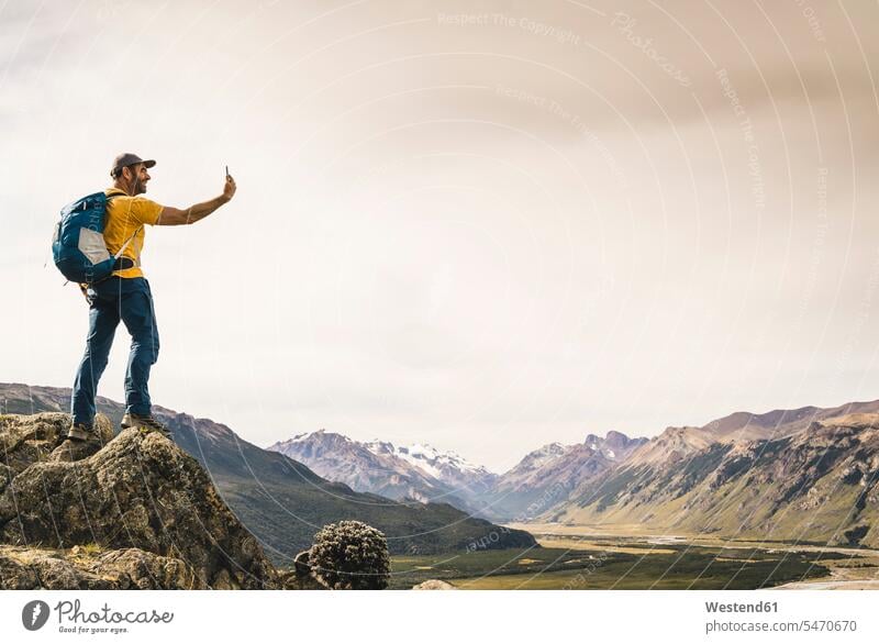Mature man taking selfie with smart phone while standing on rock against sky, Patagonia, Argentina Patagonia - Argentina South America Patagonian Andes