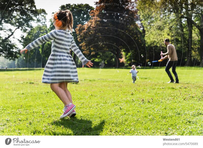 Girl with family wearing headphones in a park active girl females girls headset families parks happiness happy Activity child children kid kids people persons