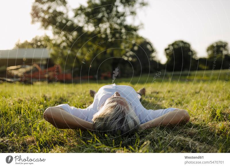 Man with hands behind head lying on grass in yard color image colour image full length full-length full body full-body full shot outdoors location shots