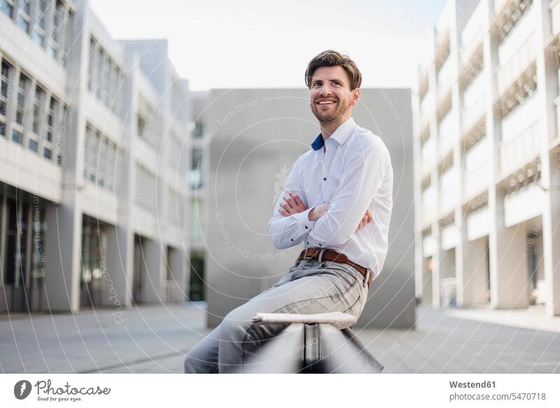 Smiling businessman sitting in the city looking around looking round look round look around town cities towns Businessman Business man Businessmen Business men