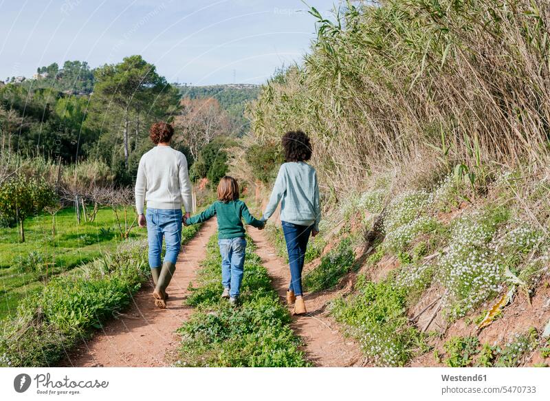Happy family walking in the countryside, holding hands going dirt track field path field paths Field Fields farmland families hand in hand rural trail people