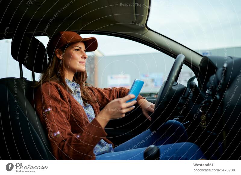 Young woman using mobile phone while sitting in car color image colour image day daylight shot daylight shots day shots daytime casual clothing casual wear