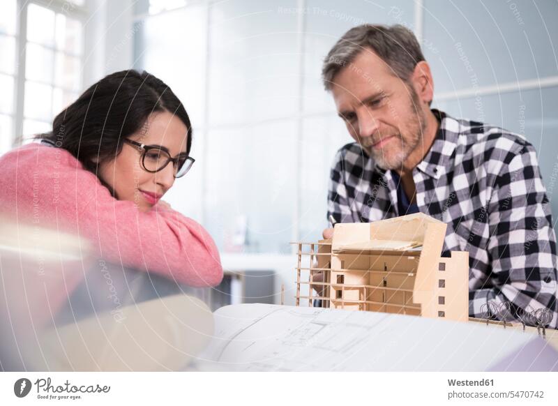 Smiling colleagues looking at architectural model in office offices office room office rooms architects Architectural Model eyeing smiling smile workplace