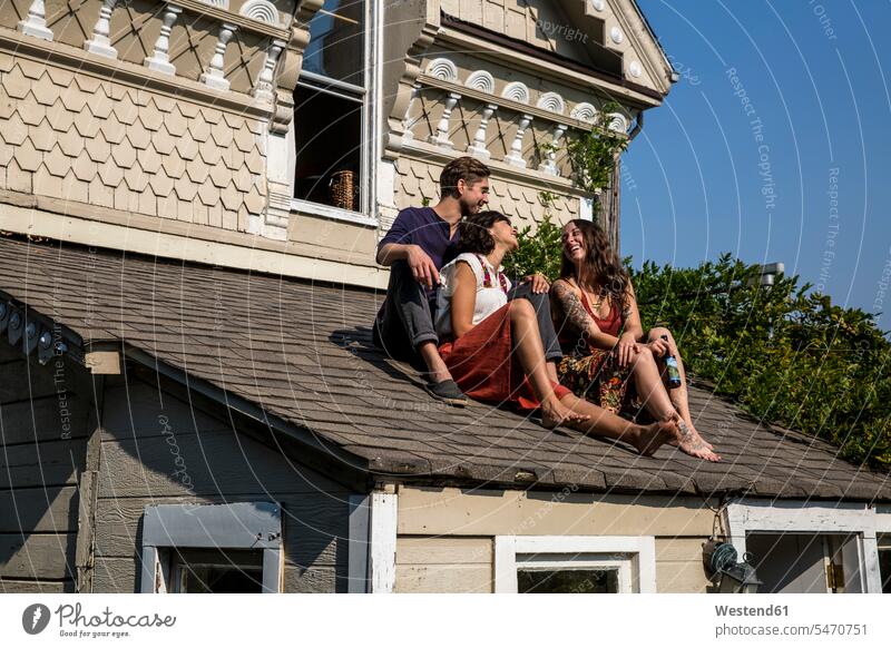 Happy friends sitting on roof mate Seated Roof friendship authenticity original nonconformity alternative lifestyle Encounter Meeting togetherness