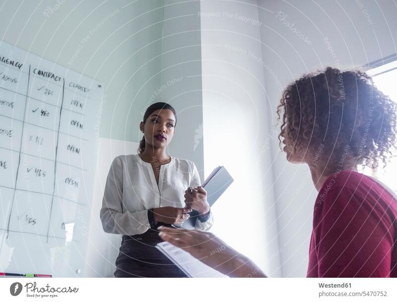 Businesswoman with female colleague discussing at office color image colour image indoors indoor shot indoor shots interior interior view Interiors day