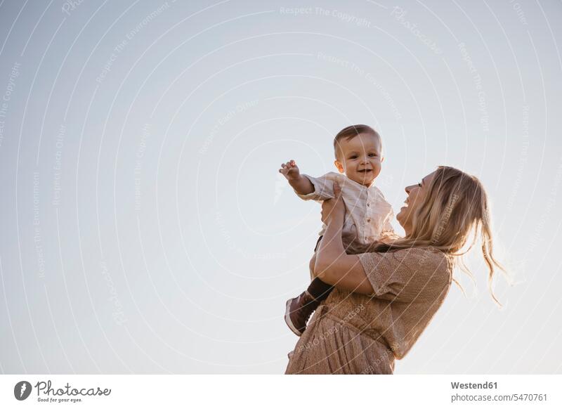 Mother holding her little son under blue sky human human being human beings humans person persons caucasian appearance caucasian ethnicity european 2 2 people