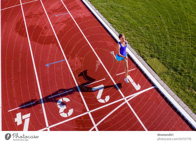 Aerial view of a running young female athlete on a tartan track crossing finishing line human human being human beings humans person persons
