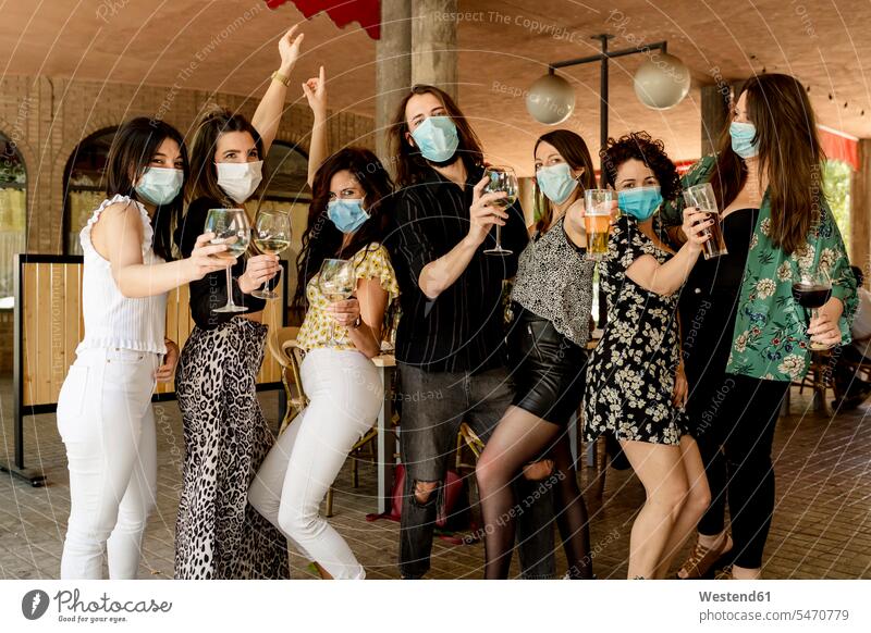 Young male and female customers holding drinks while standing at restaurant during pandemic color image colour image Spain indoors indoor shot indoor shots