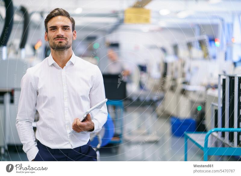 Confident young businessman holding digital tablet while standing at illuminated factory color image colour image indoors indoor shot indoor shots interior