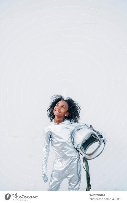 Portrait of smiling little girl wearing space suit in front of white background looking up transport space travel spacemen astronauts gloves smile delight
