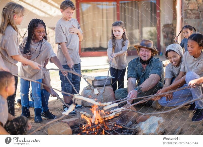 Children and guide roasting twist bread at camp fire child children kid kids Camp Fire Campfire Bonfire Guide people persons human being humans human beings