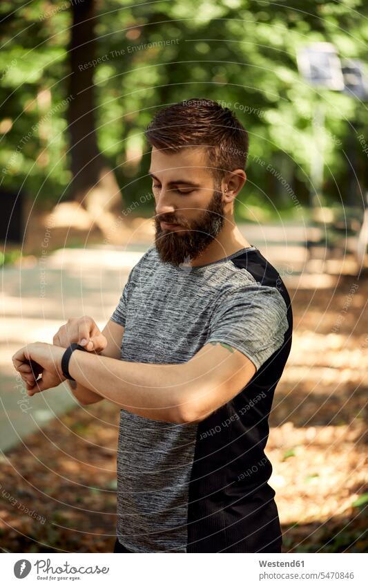 Sporty man in forest checking his smartwatch human human being human beings humans person persons caucasian appearance caucasian ethnicity european 1