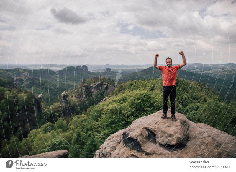 Germany, Saxony, Elbe Sandstone Mountains, man on a hiking trip standing on rock cheering hike rocks hiking tour walking tour men males jubilate rejoicing