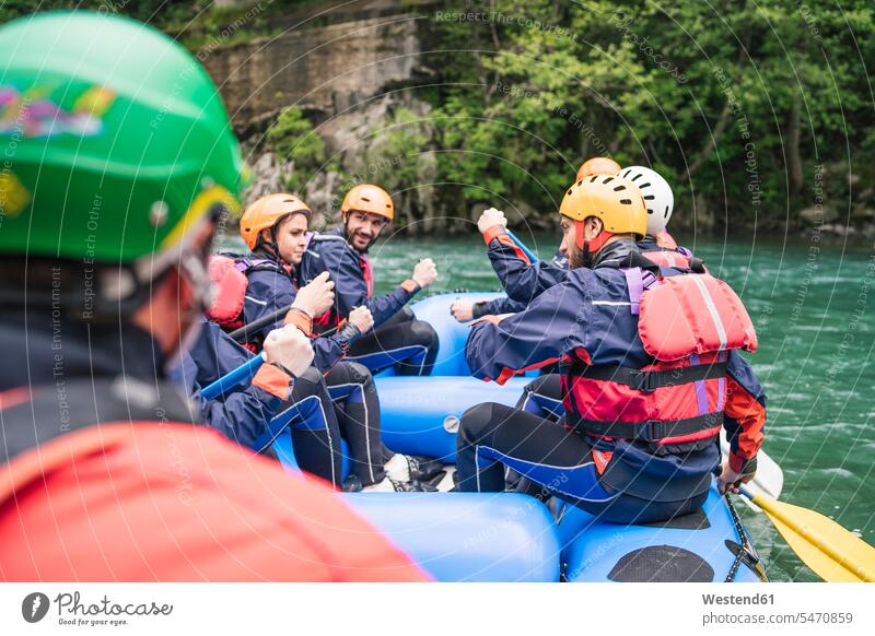 Group of people rafting in rubber dinghy on a river friends mate delight enjoyment Pleasant pleasure free time leisure time protect protecting safe Safety
