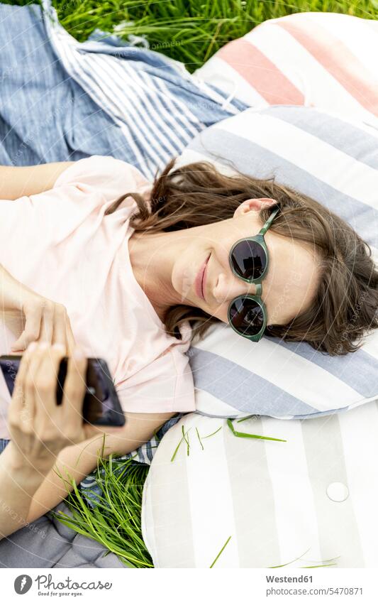 Relaxed woman lying on a meadow using cell phone smile SMS Text Message human human being human beings humans person persons adult grown-up grown-ups grownup