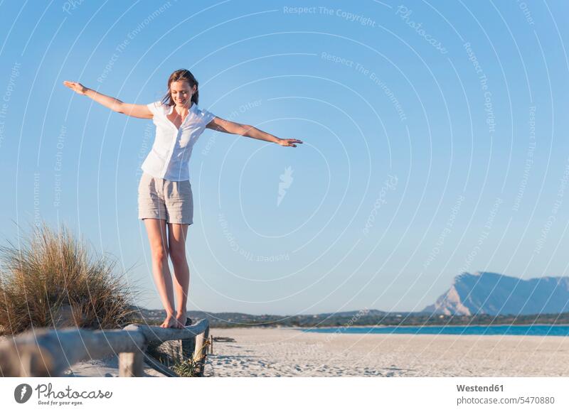 Smiling woman balancing on fence on the beach, Sardinia, Italy balanced Equilibrium relax relaxing go going walk free time leisure time Lifestyle holiday