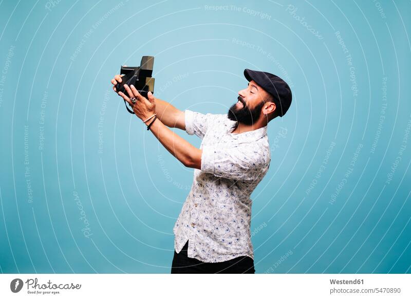Bearded young man in studio taking selfie with instant camera photographers images picture pictures photographs photos instant photograph instant photography