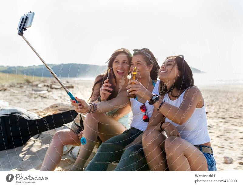 Happy female friends with beer bottles taking a selfie on the beach human human being human beings humans person persons caucasian appearance