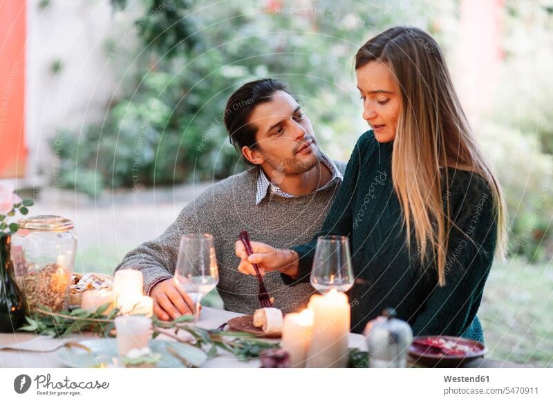 Romantic couple having a candlelight meal at garden table romantic lyrical Romance eating Meals twosomes partnership couples candle light Food foods