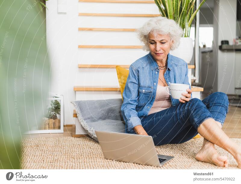 Mature woman working on laptop while sitting at home color image colour image indoors indoor shot indoor shots interior interior view Interiors day