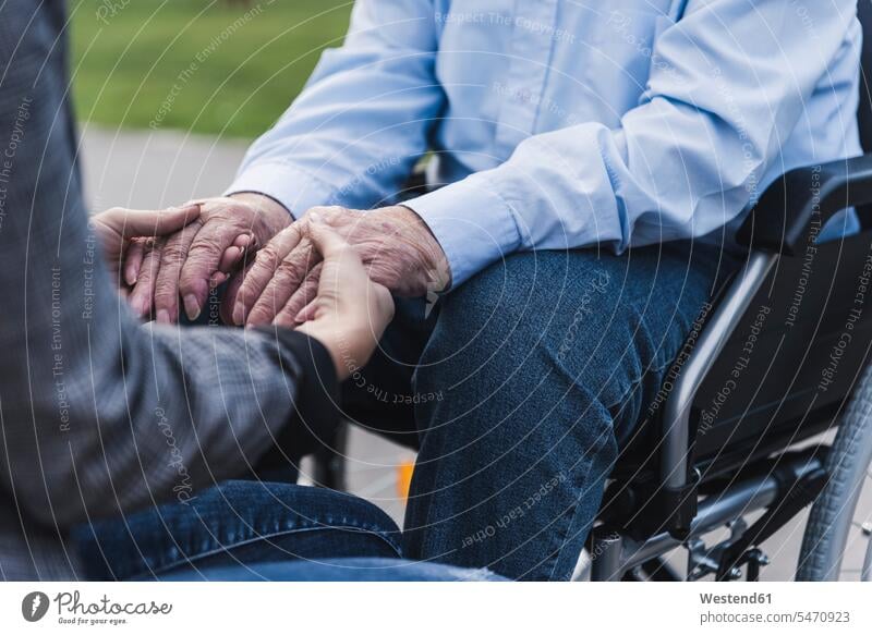 Young woman holding hands of senior man sitting in wheel chair, partial view generation wheelchairs touch Seated Emotions Feeling Feelings Sentiment Sentiments