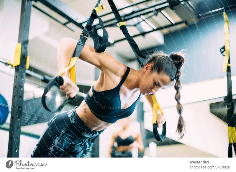 Young woman doing suspension traning in the gym exercise practising train training hold exercising practice practise pull sports fit free time leisure time